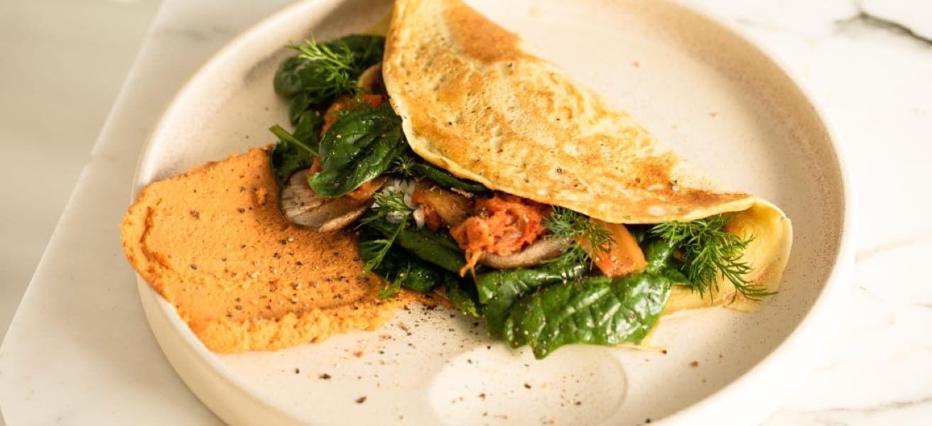 a delicious looking omelette with veggie fillings and bread on a white plate